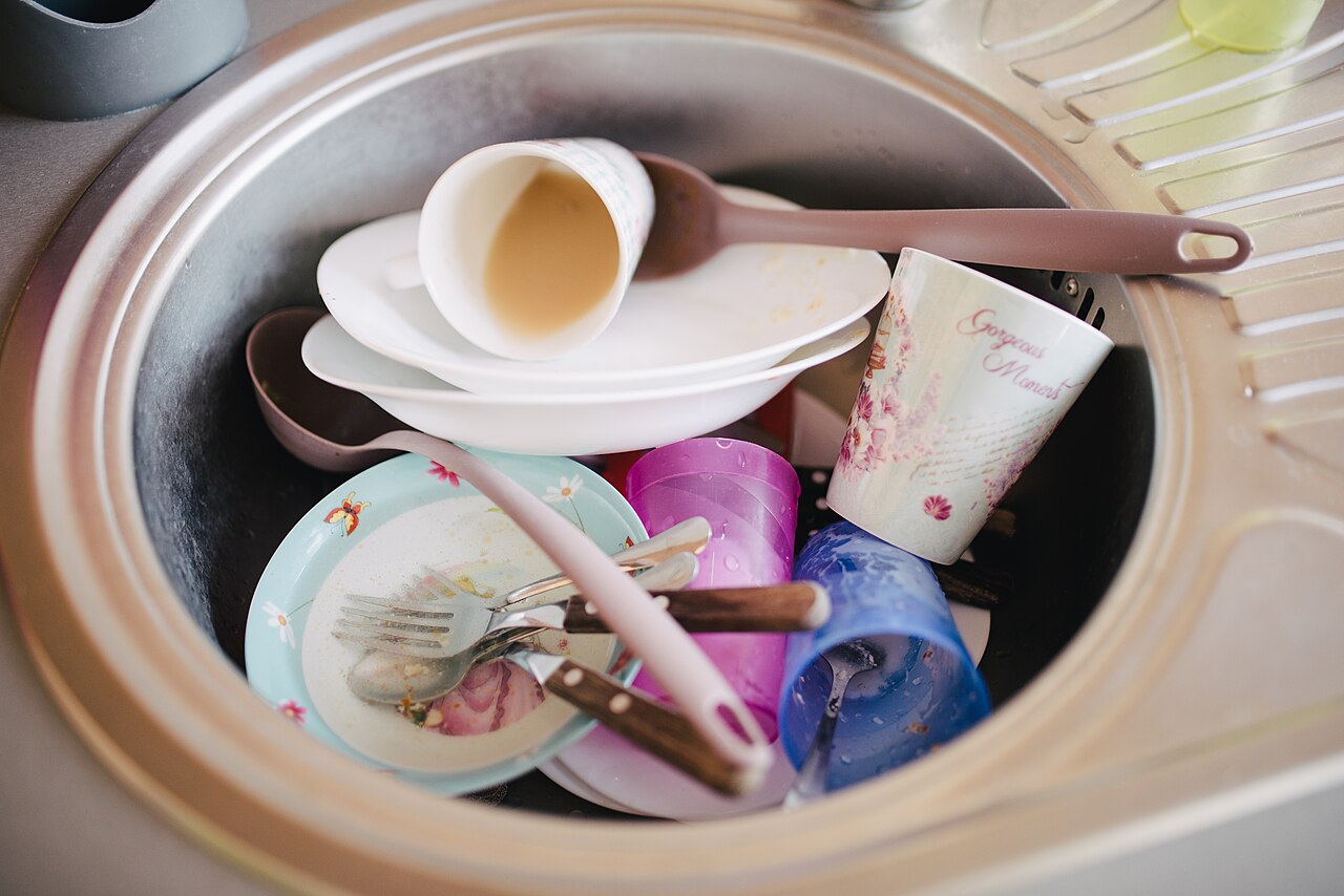 Used plates, cups and cutlery left in a kitchen sink