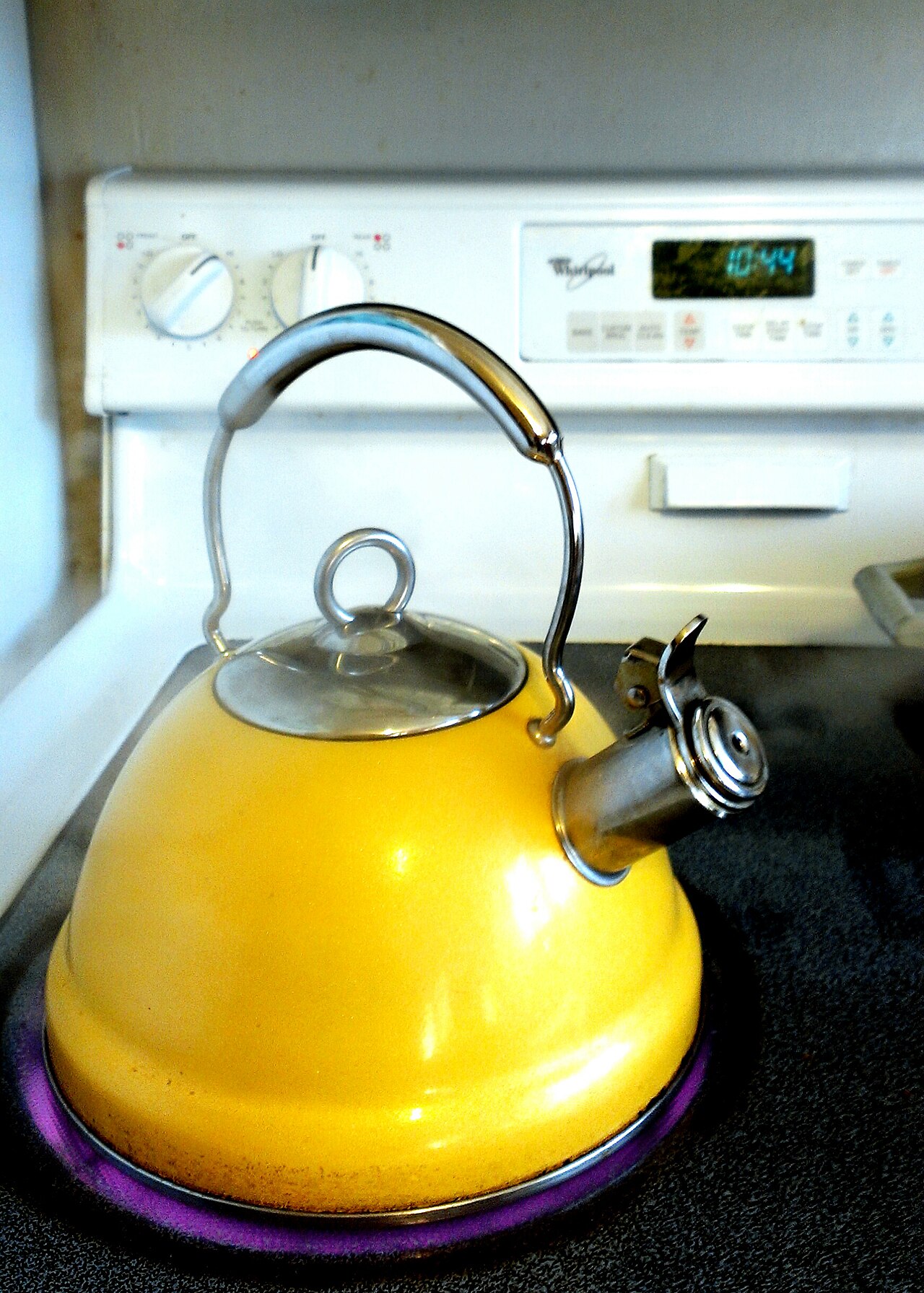Yellow kettle with water boiling on a stovetop