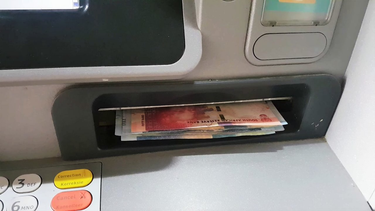 Rand banknotes in the cash slot of a South African ATM