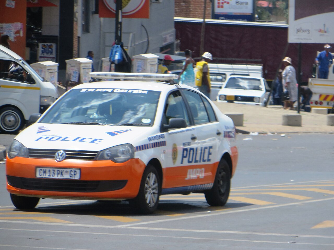 A white and orange Johannesburg Metro Police (JMPD) patrol car on a city street